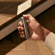 Close-up of a man’s hand turning on the Ploom AURA Lunar Silver device to begin the heating process smoothly.