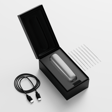 Open box of Ploom AURA Lunar Silver showing the device, charging cable, and cleaning accessories inside the package.