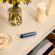 Ploom AURA device resting on a table with Navy Blue Augmented Pattern front panel attached, blending seamlessly into a clean, everyday setting.
