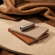 Ploom AURA front panels with Lunar Silver Augmented Pattern placed on stacked notebooks, creating a creative lifestyle scene with modern appeal.
