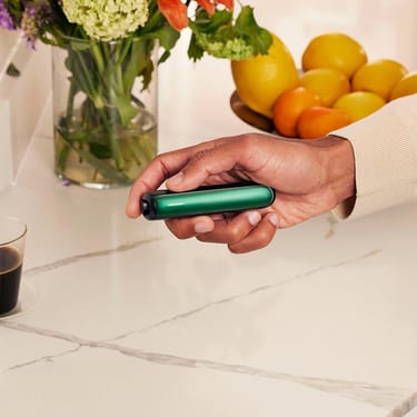 Hand holding a Ploom device with Amazon Green Front Panel, showing comfortable grip, compact design, and a sense of personalized everyday use.
