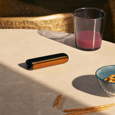 Ploom AURA Mango Sorbet front panel attached to device on a table, demonstrating sleek modularity and vibrant color personalization options.