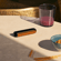 Ploom AURA Mango Sorbet front panel attached to device on a table, demonstrating sleek modularity and vibrant color personalization options.