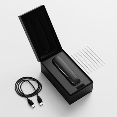 Open box view of Ploom AURA displaying the device, charging cable, and cleaning sticks neatly arranged inside the packaging.
