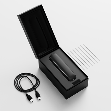 Open box view of Ploom AURA displaying the device, charging cable, and cleaning sticks neatly arranged inside the packaging.
