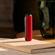Ploom device with Lava Red Back Cover placed standing on top of a book, adding a bold accent to a relaxed moment at home or work