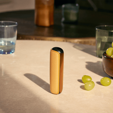Ploom device with Mango Sorbet Back Cover standing on a table, highlighting smooth, glossy finish, vivid shade, and sleek modern minimalist style
