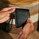 Tangan memegang Jet Black Duo Carry Case, menonjolkan bentuk padat, genggaman selamat dan kemasan luar premium.
