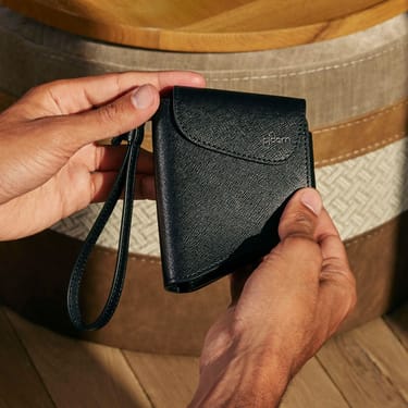 Tangan memegang Jet Black Duo Carry Case, menonjolkan bentuk padat, genggaman selamat dan kemasan luar premium.