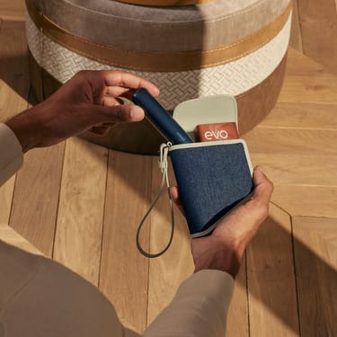 Hand taking a Ploom AURA Navy Blue  device out of the Ploom Duo Carry Case Denim Leather Fusion