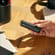 Hand showing a Jet Black Back Cover on a Ploom AURA device, demonstrating smooth design and easy personalization for daily routines