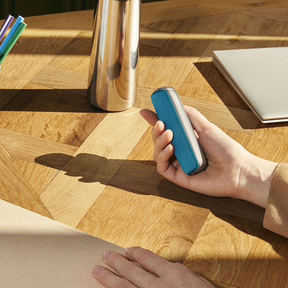 Hand holding a Ploom AURA with Ocean Blue Back Cover, showing a soothing color that feels comfortable and natural to use.
