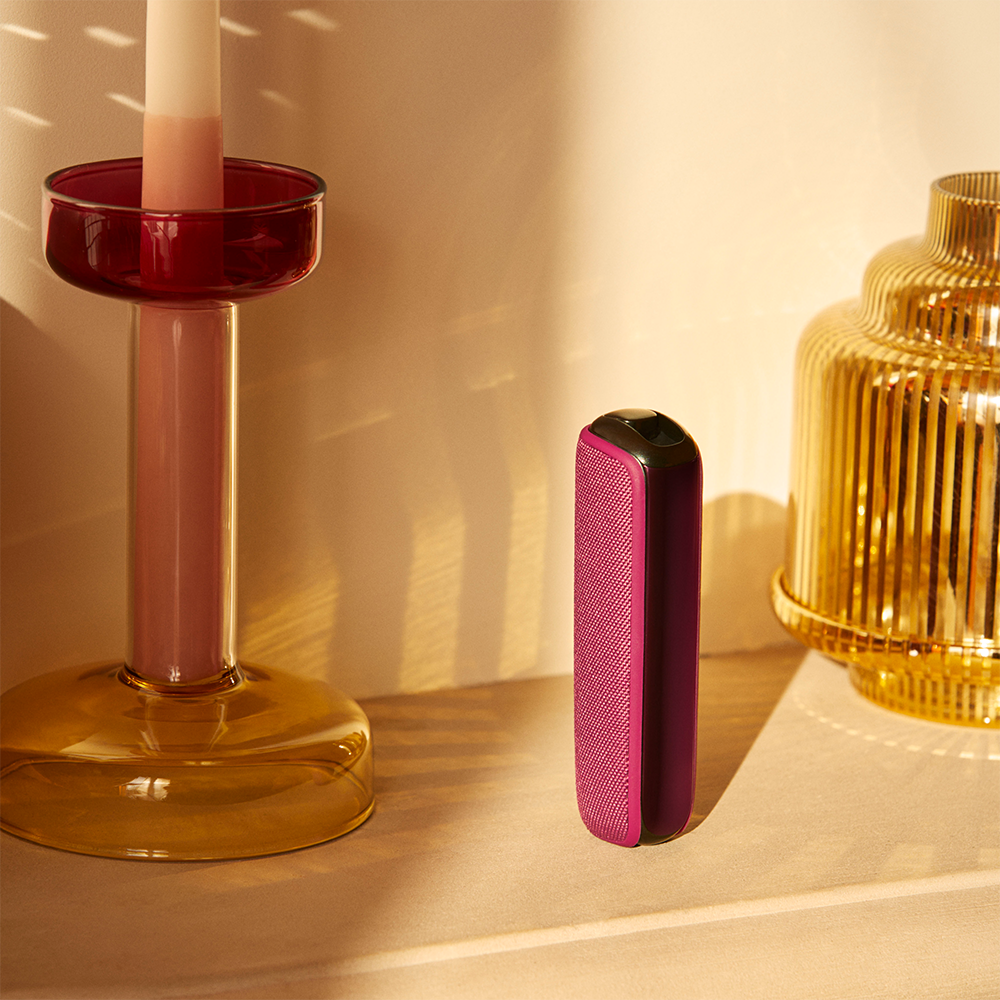 Ploom AURA Dark Orchid device standing on a table, presenting a confident and elegant color that draws attention without feeling excessive.
