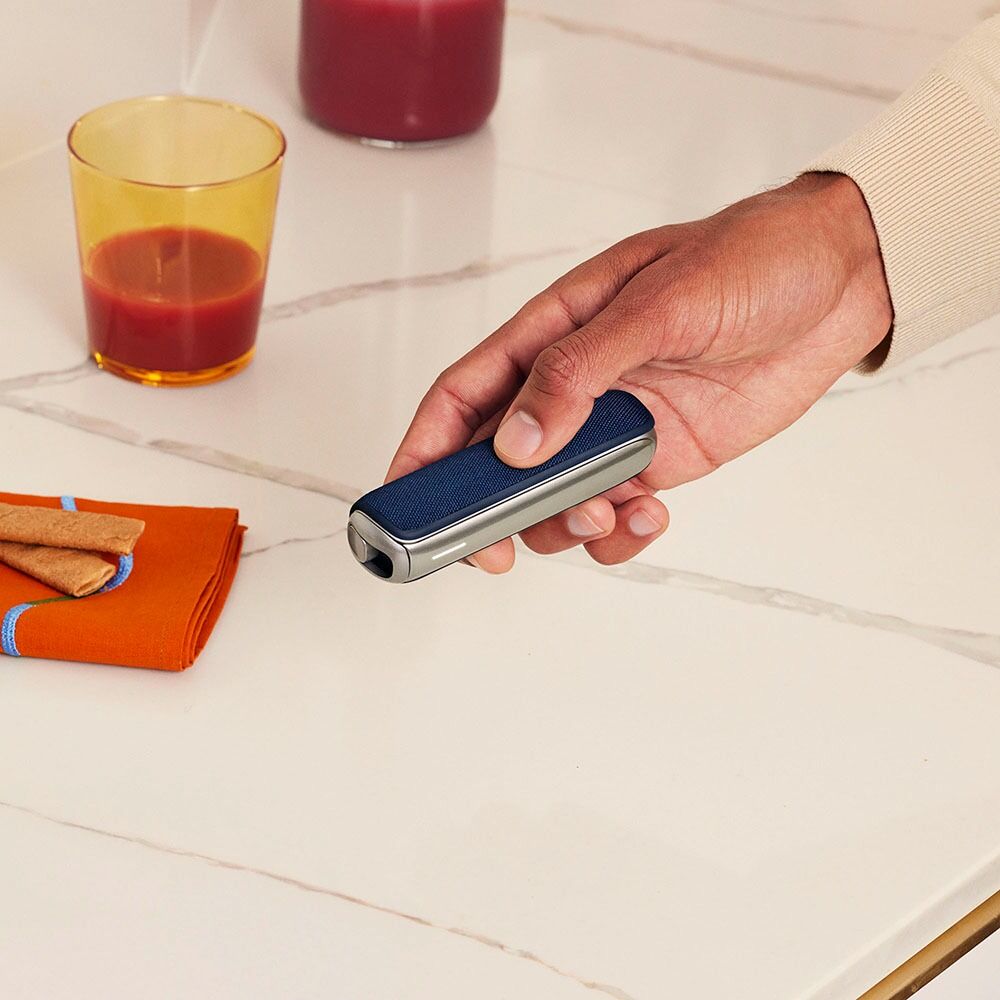 Hand holding a Ploom AURA device with Navy Blue Back Cover, showcasing elegant tone and smooth finish for a polished, everyday lifestyle.
